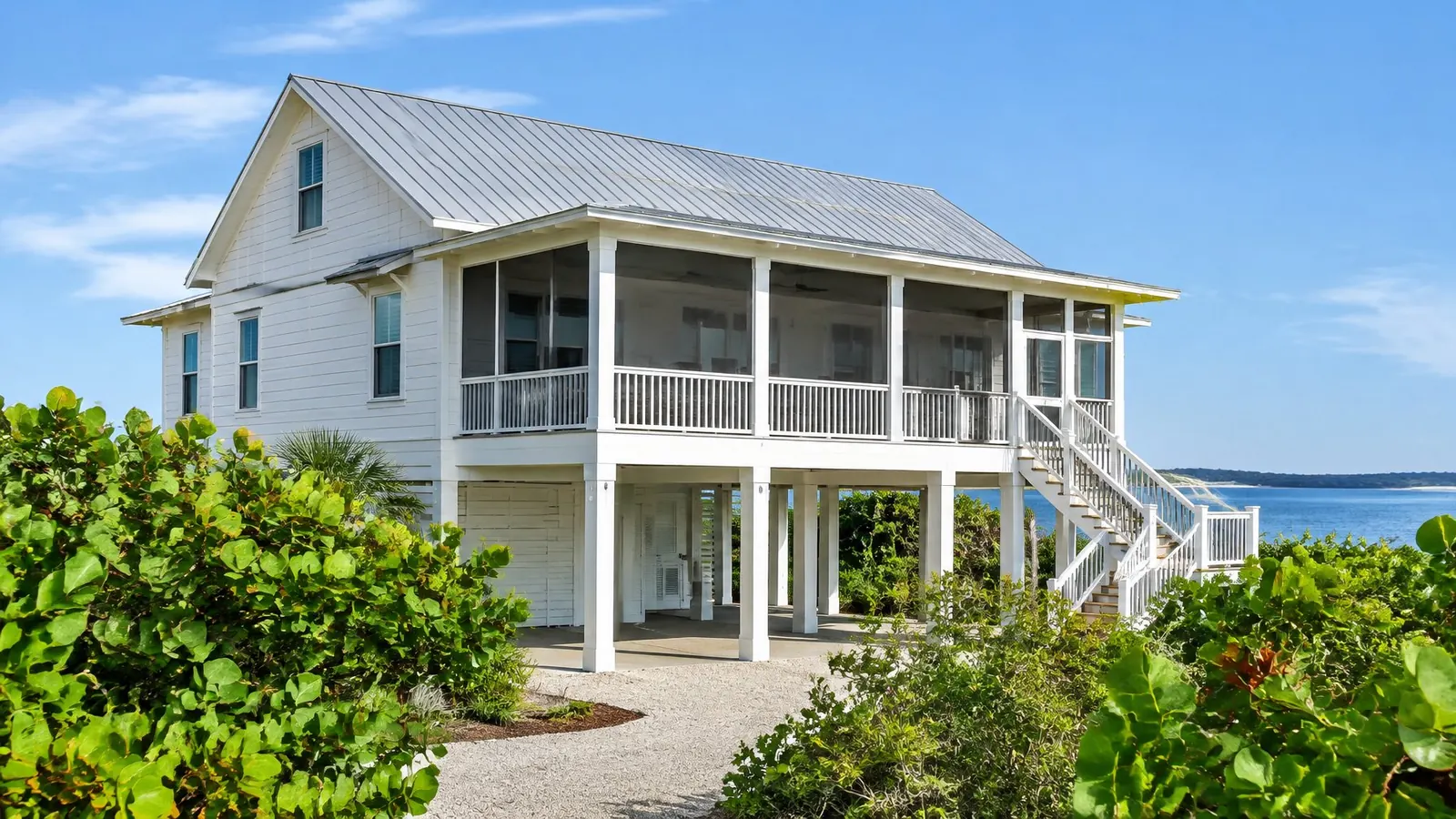 Raised coastal Florida home with a light gray standing-seam metal roof near the water
